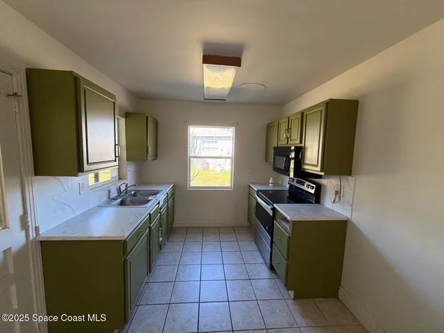 a room with a sink a flat screen tv and windows