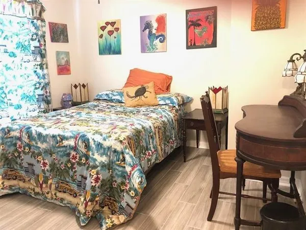 a bedroom with a bed and dresser with wooden floor