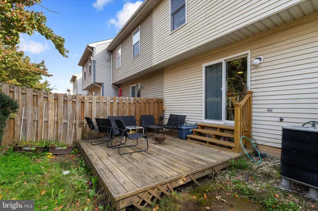 a view of backyard with table and chairs plants and wooden fence