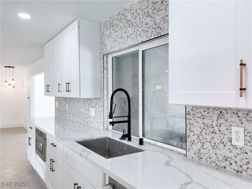 4501 South Woodcrest Road Las Vegas, NV 89121 - Photo 13 of 78 Kitchen featuring light stone counters, white cabinets, hanging light fixtures, decorative backsplash, and recessed lighting