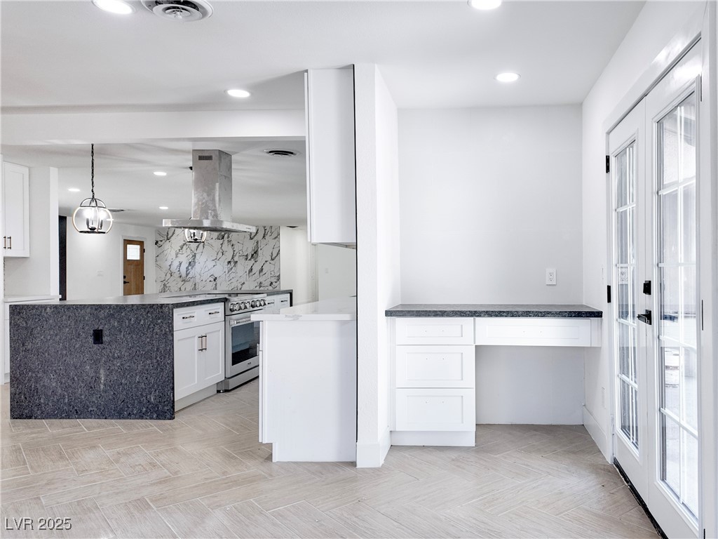 4501 South Woodcrest Road Las Vegas, NV 89121 - Photo 27 of 78 Kitchen with white cabinetry, island range hood, high end stainless steel range, recessed lighting, and tasteful backsplash