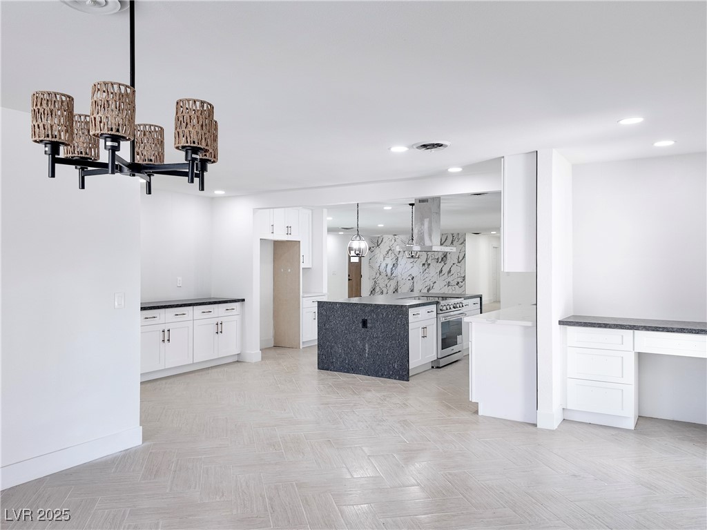 4501 South Woodcrest Road Las Vegas, NV 89121 - Photo 28 of 78 Kitchen featuring white cabinets, hanging light fixtures, decorative backsplash, a chandelier, and electric stove