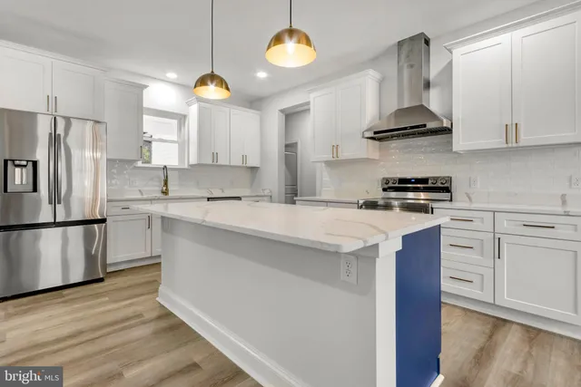 a kitchen with stainless steel appliances granite countertop a sink a stove a refrigerator and island with wooden floor