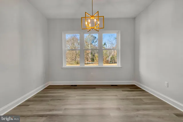 an open kitchen with wooden floor and chandelier