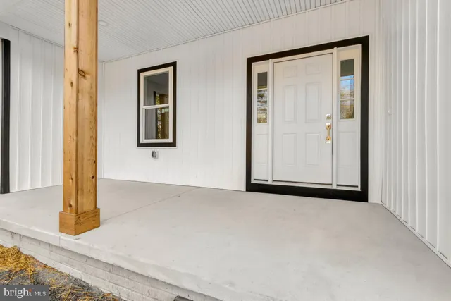 a view of a hallway with wooden floor and a bathroom