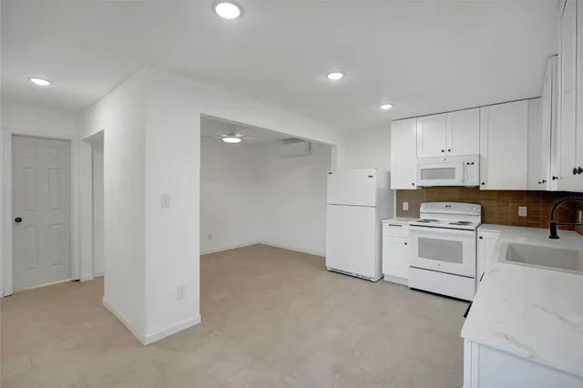 a kitchen with granite countertop white cabinets and white appliances