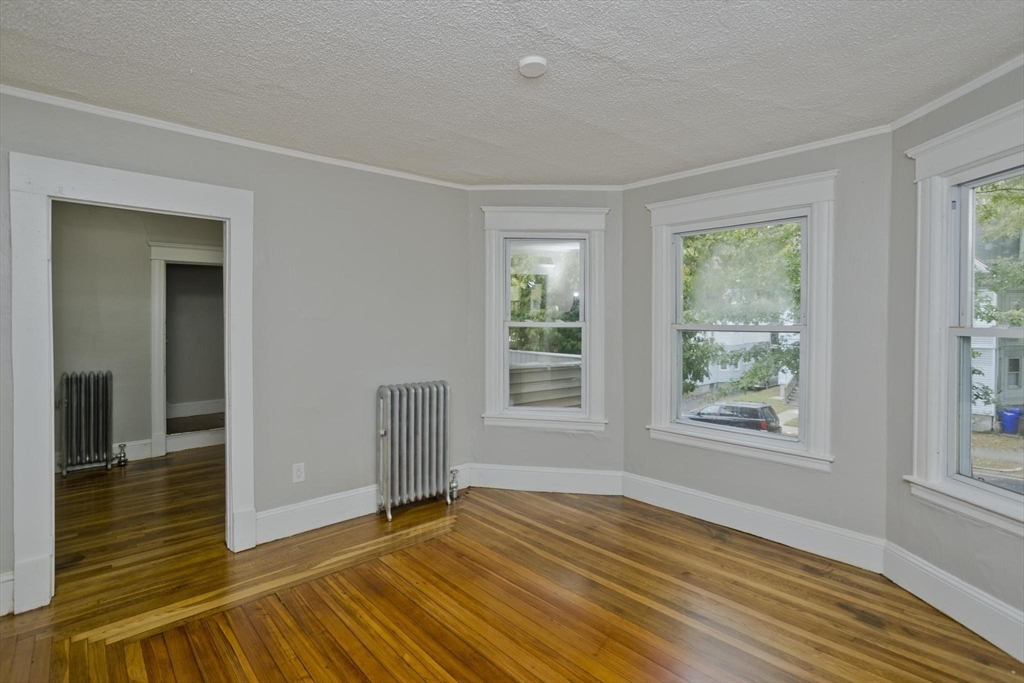 107 Orange Street Springfield, MA 01108 - Photo 7 of 38 a view of an empty room with wooden floor and a window