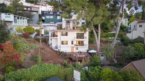 an aerial view of residential houses with outdoor space and trees