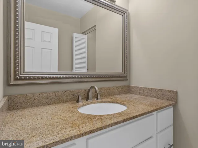 a bathroom with a granite countertop sink and a mirror