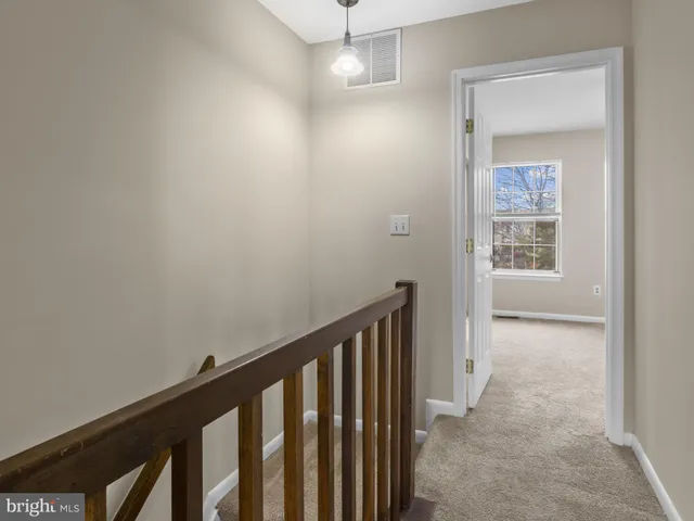 a view of a hallway with wooden floor and a bathroom