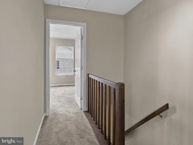 a view of a hallway with a door and a refrigerator