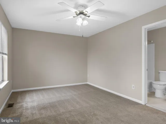 an empty room with a chandelier fan and windows