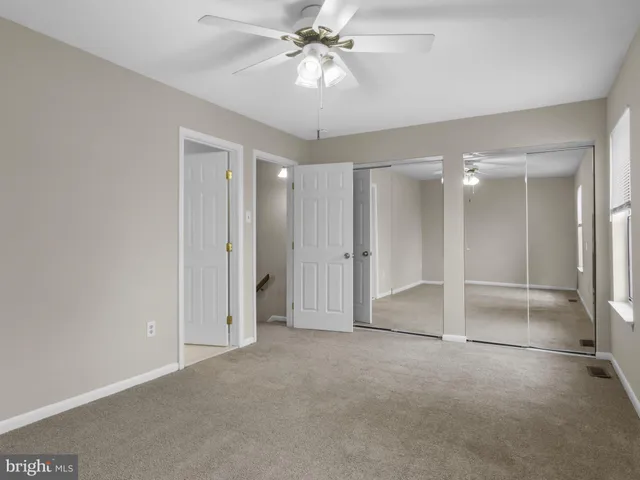 a view of an empty room and a chandelier fan