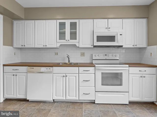 a kitchen with white cabinets and white appliances