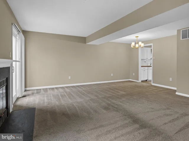 a view of an empty room with window and chandelier fan