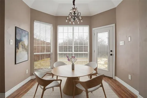 a dining room with chandelier and wooden floor