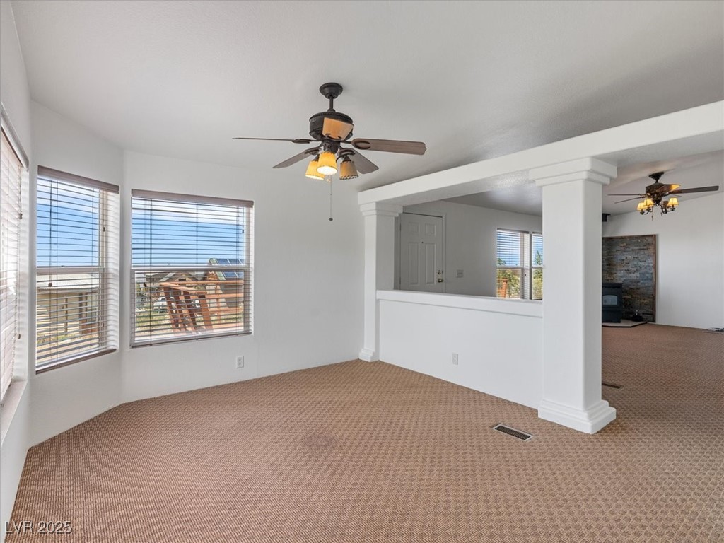70 West Bonanza Road Las Vegas, NV 89124 - Photo 23 of 71 Carpeted spare room featuring a ceiling fan, ornate columns, and a glass covered fireplace