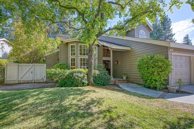 a view of a house with a small yard plants and large tree