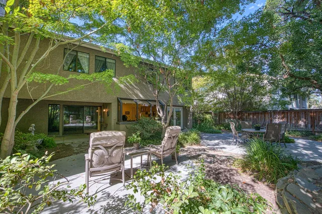 a view of a chair and table in backyard of the house