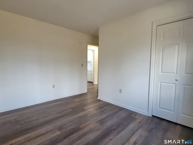 a view of an empty room with wooden floor and closet