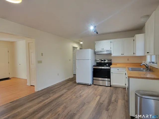 a kitchen with a refrigerator a stove top oven and white cabinets
