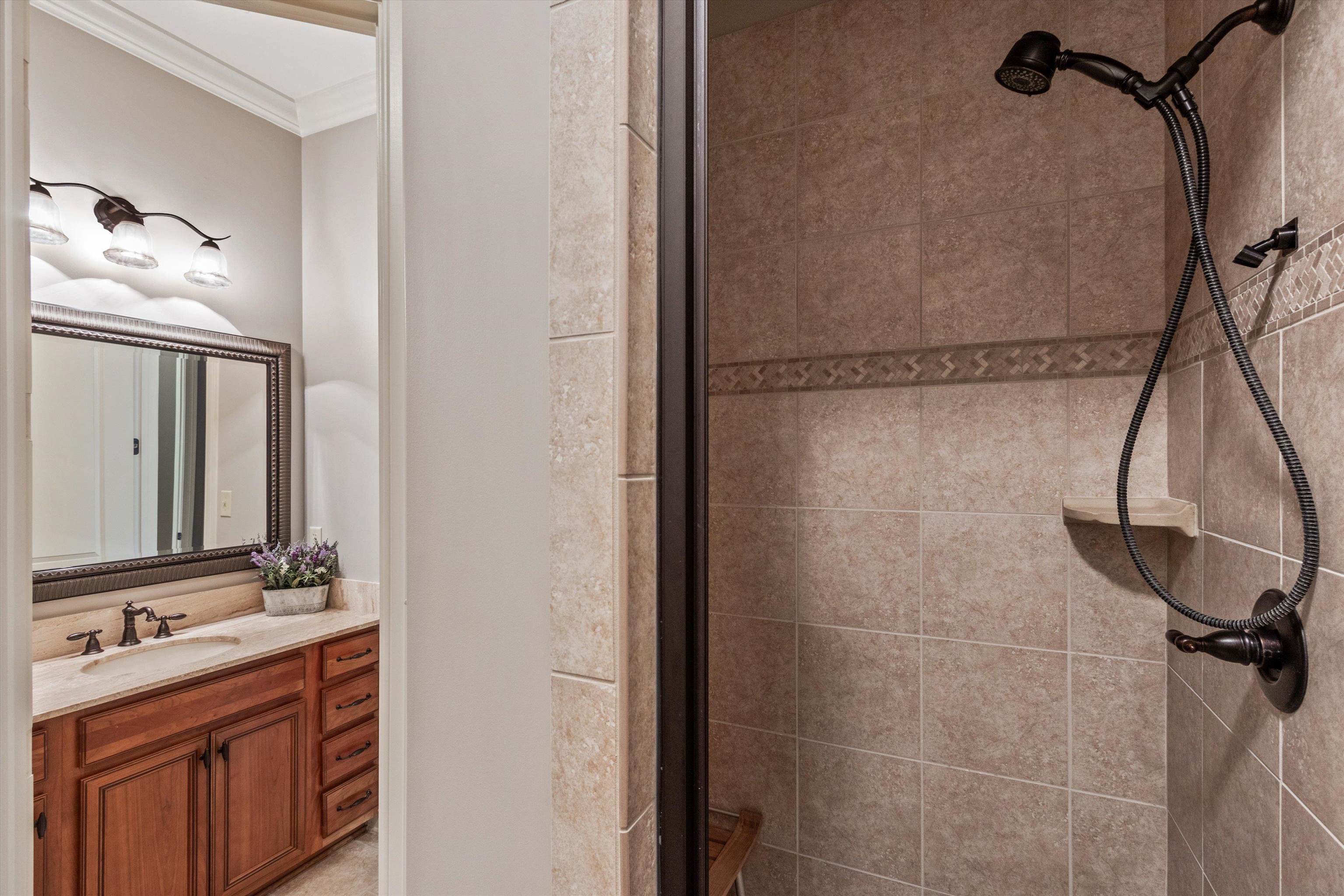 150 Ridgecrest Drive Arlington, TN 38002 - Photo 24 of 40 Bathroom with a tiled shower stall featuring a handheld and fixed shower head, decorative accent tile band, and a corner shelf
