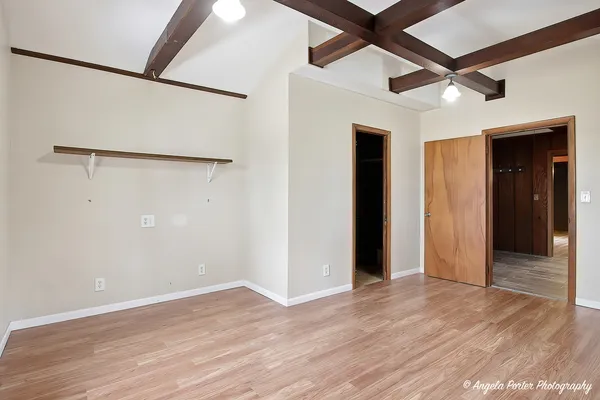 an empty room with wooden floor and a ceiling fan