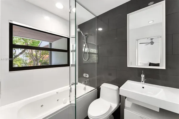 a bathroom with a toilet a sink a tub and a large mirror