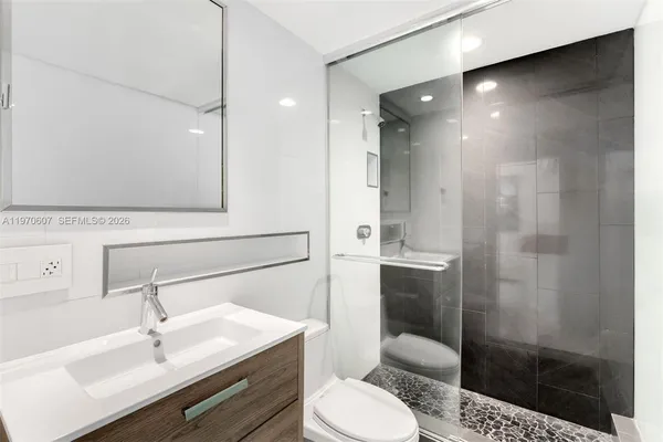 a bathroom with a sink toilet a mirror and shower