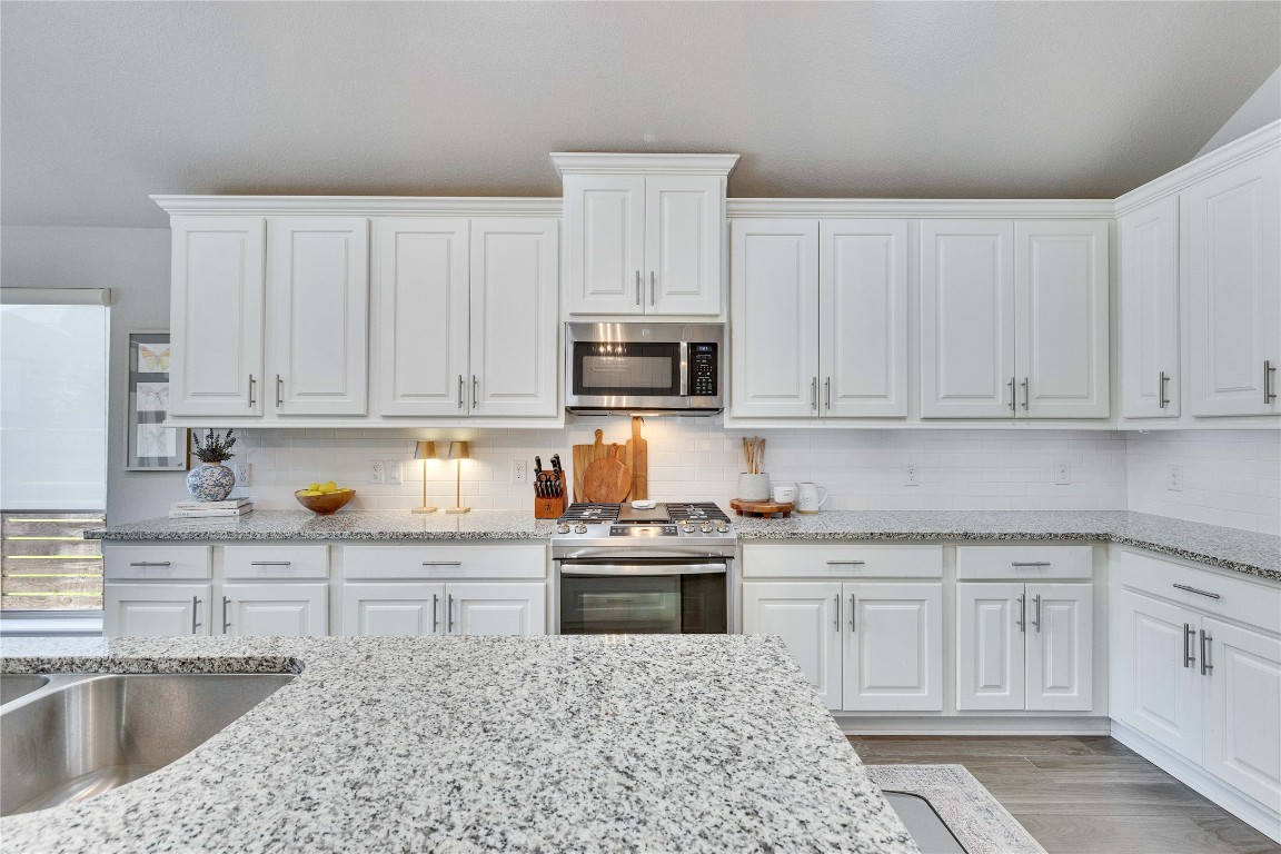 4229 Mercer Road Georgetown, TX 78628 - Photo 12 of 38 Kitchen featuring stainless steel appliances, light stone countertops, and white cabinetry