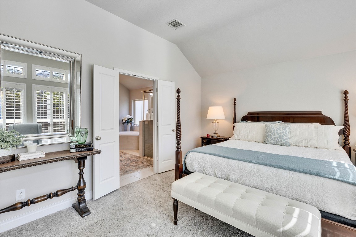 4229 Mercer Road Georgetown, TX 78628 - Photo 16 of 38 Bedroom with visible vents, carpet flooring, ensuite bathroom, and vaulted ceiling