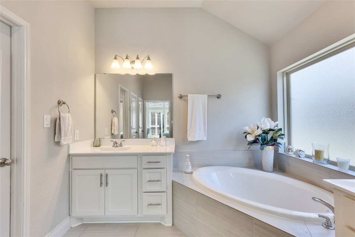 4229 Mercer Road Georgetown, TX 78628 - Photo 18 of 38 Bathroom with vanity, tile patterned flooring, lofted ceiling, and a bath