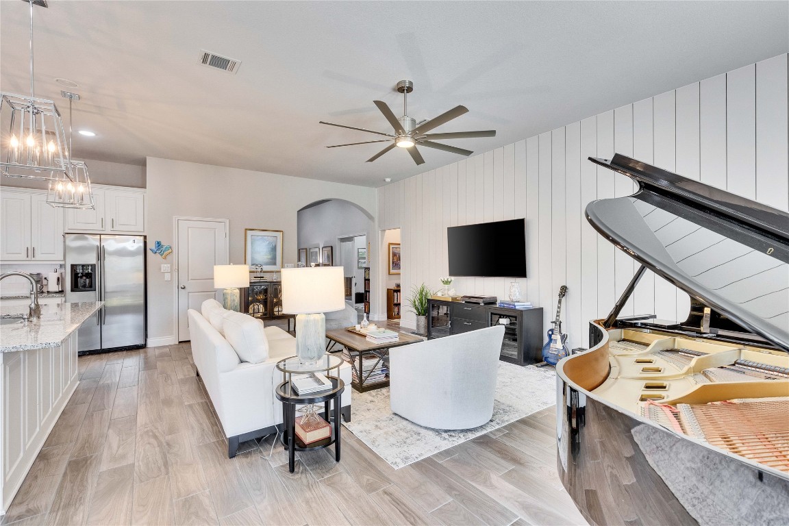 4229 Mercer Road Georgetown, TX 78628 - Photo 5 of 38 Living room with light wood finished floors, arched walkways, ceiling fan with notable chandelier, baseboards, and visible vents