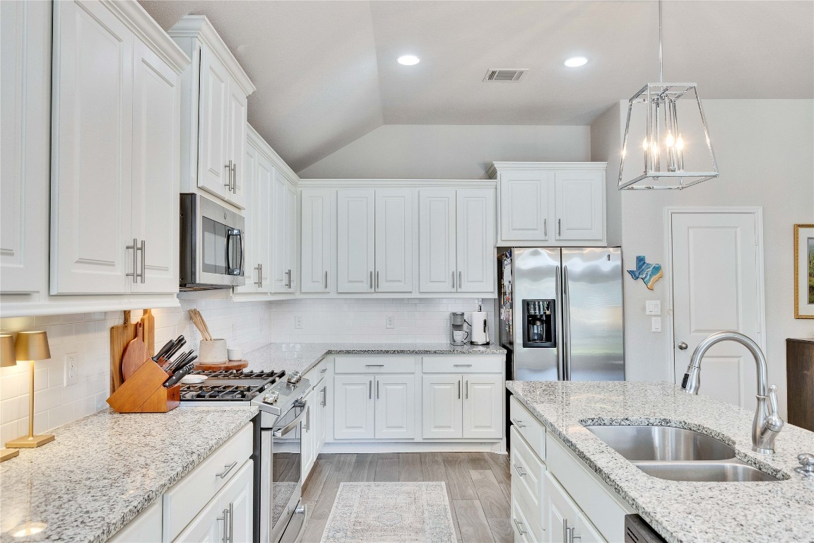 4229 Mercer Road Georgetown, TX 78628 - Photo 10 of 38 Kitchen with visible vents, appliances with stainless steel finishes, white cabinetry, a sink, and light wood-style flooring