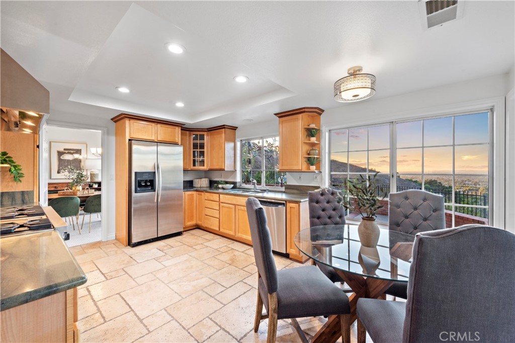 6129 East Joan D Arc Circle Orange, CA 92869 - Photo 9 of 27 a kitchen with stainless steel appliances kitchen island granite countertop a refrigerator a stove top oven a sink and a dining table with the view