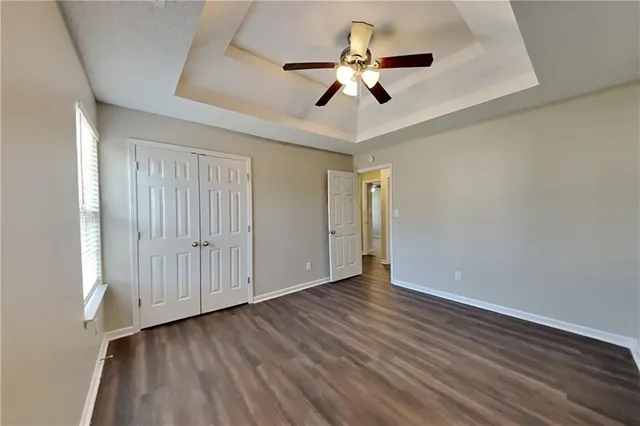 a view of an empty room with wooden floor and a ceiling fan