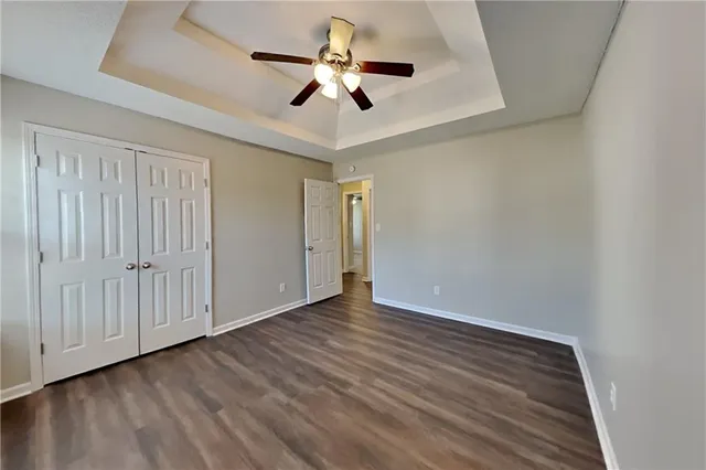 wooden floor in an empty room with a chandelier fan