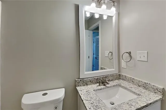 a bathroom with a granite countertop sink a toilet and mirror