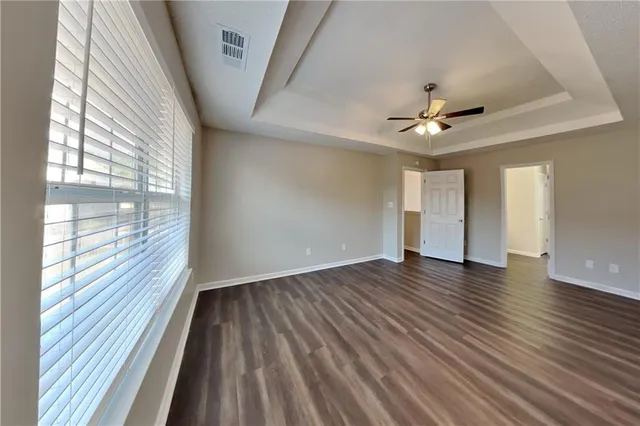 a view of an empty room with a window and wooden floor