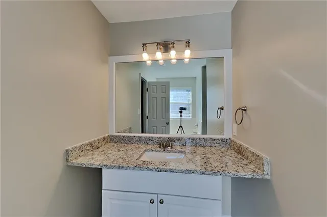 a bathroom with a granite countertop sink and a mirror