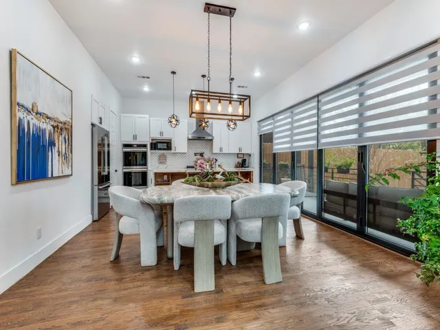 a dining room with wooden floor a chandelier a glass table and chairs
