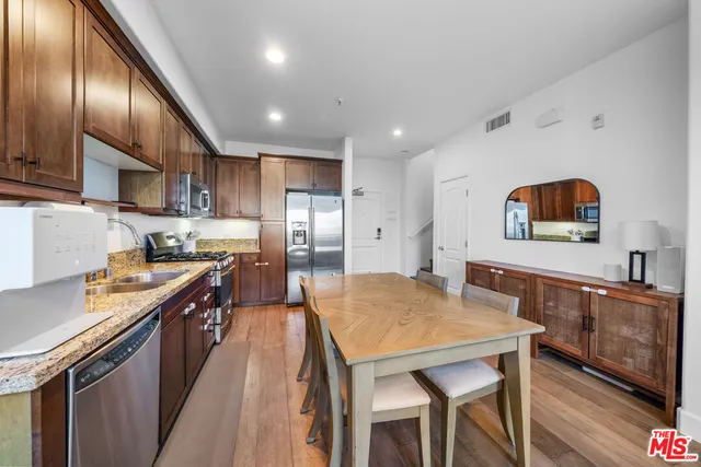 a kitchen with stainless steel appliances granite countertop a stove top oven a sink a dining table and chairs