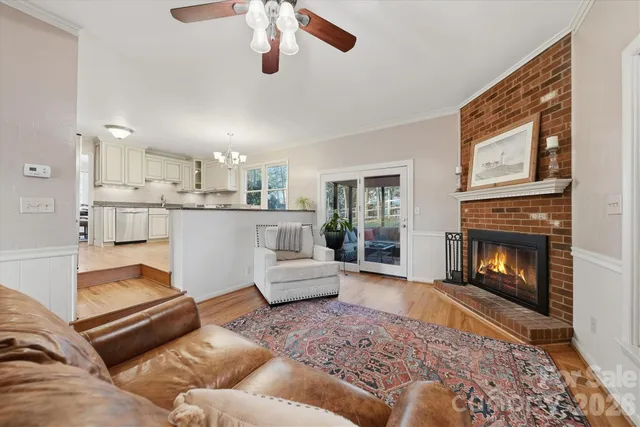 a living room with stainless steel appliances furniture a fireplace and a chandelier