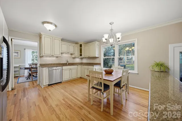 a kitchen with a table chairs a sink dishwasher window and cabinets