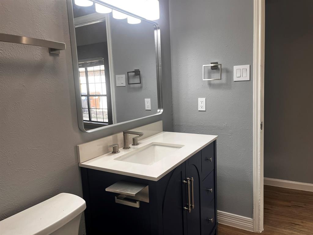 1007 Mack Place Denton, TX 76209 - Photo 34 of 37 Half bath with a textured wall, vanity, and dark wood-style floors