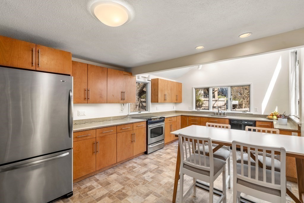 24 Flintlock Road Lexington, MA 02420 - Photo 15 of 33 a kitchen with stainless steel appliances granite countertop a refrigerator a stove a sink dishwasher with a dining table and chairs