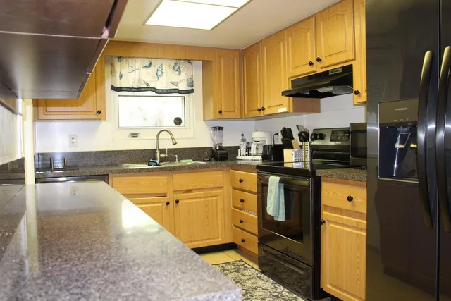 a kitchen with stainless steel appliances granite countertop a sink a stove and a refrigerator