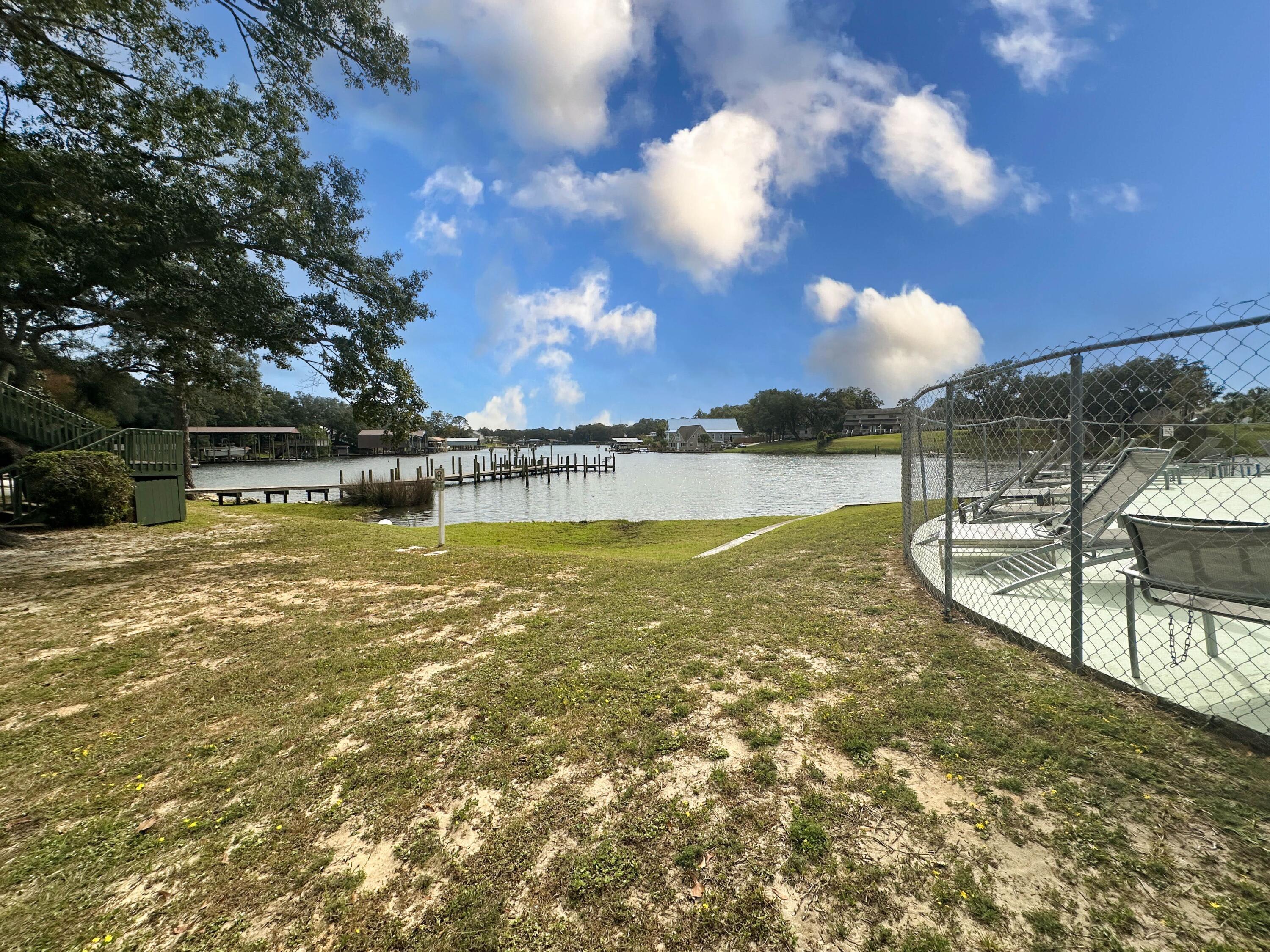 210 Pelham Road, Unit 103B Fort Walton Beach, FL 32547 - Photo 1 of 19 a view of a lake with houses in the back