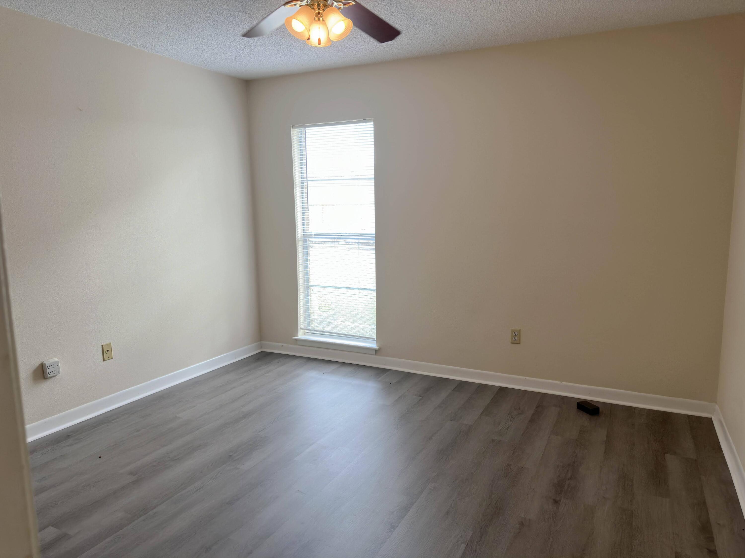 210 Pelham Road, Unit 103B Fort Walton Beach, FL 32547 - Photo 11 of 19 an empty room with wooden floor and windows