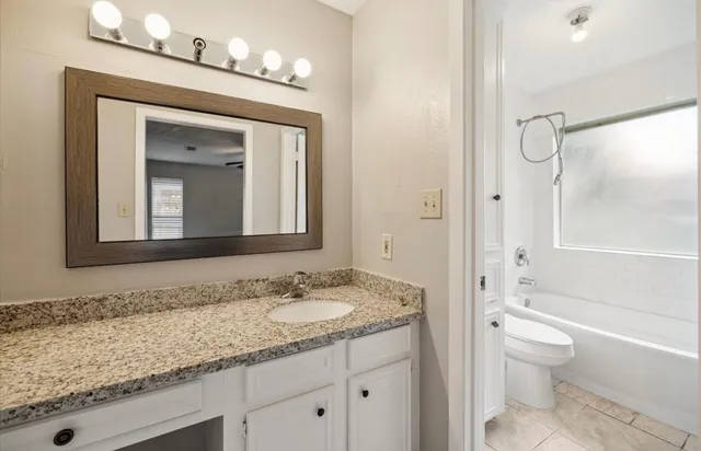 a bathroom with a granite countertop sink toilet and shower